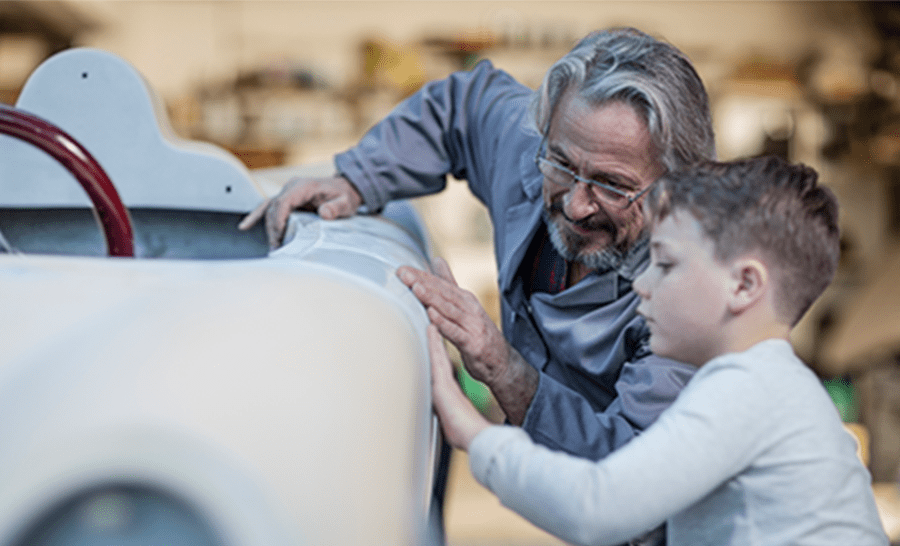 Older gentleman with grandchild polishing the side of a classic car